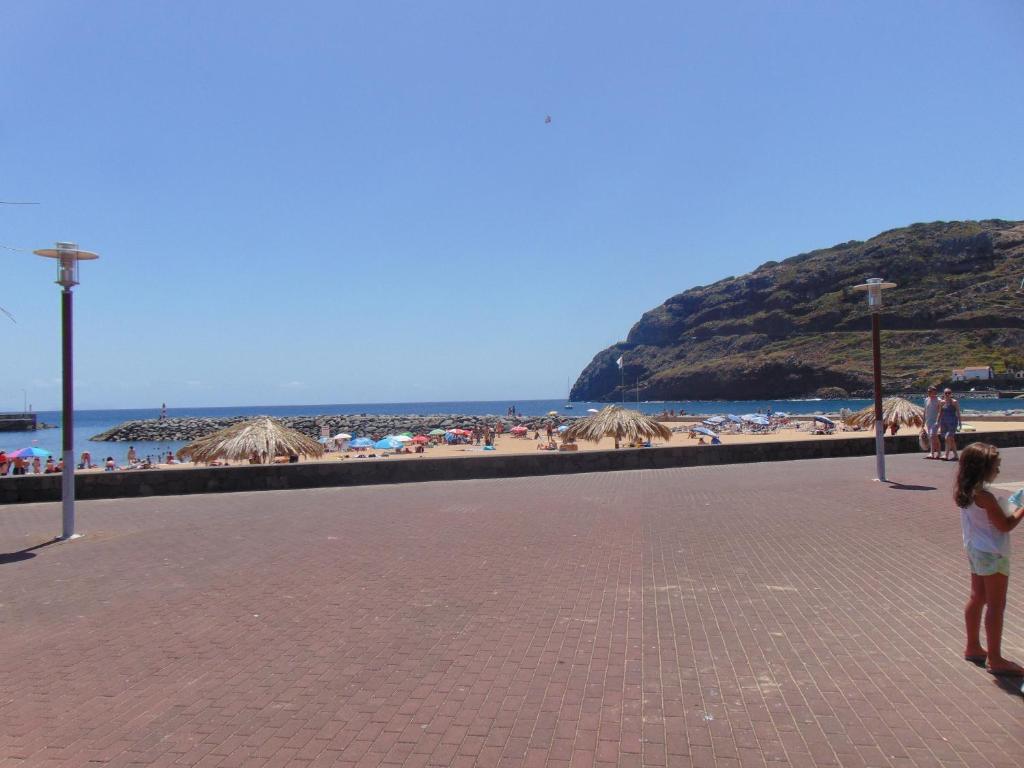 a little girl standing on a sidewalk near the beach at Marques House in Machico