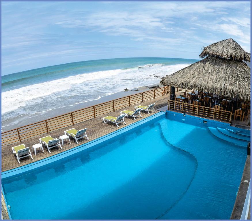 a swimming pool next to the ocean with a beach at Akas Hotel Apartamentos in Canoas De Punta Sal
