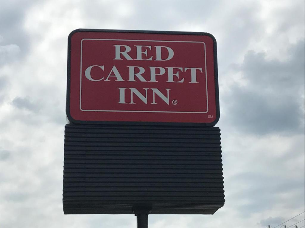 un panneau rouge indiquant l'auberge au-dessus d'un poteau dans l'établissement Red Carpet Inn, Alexandria, à Alexandria