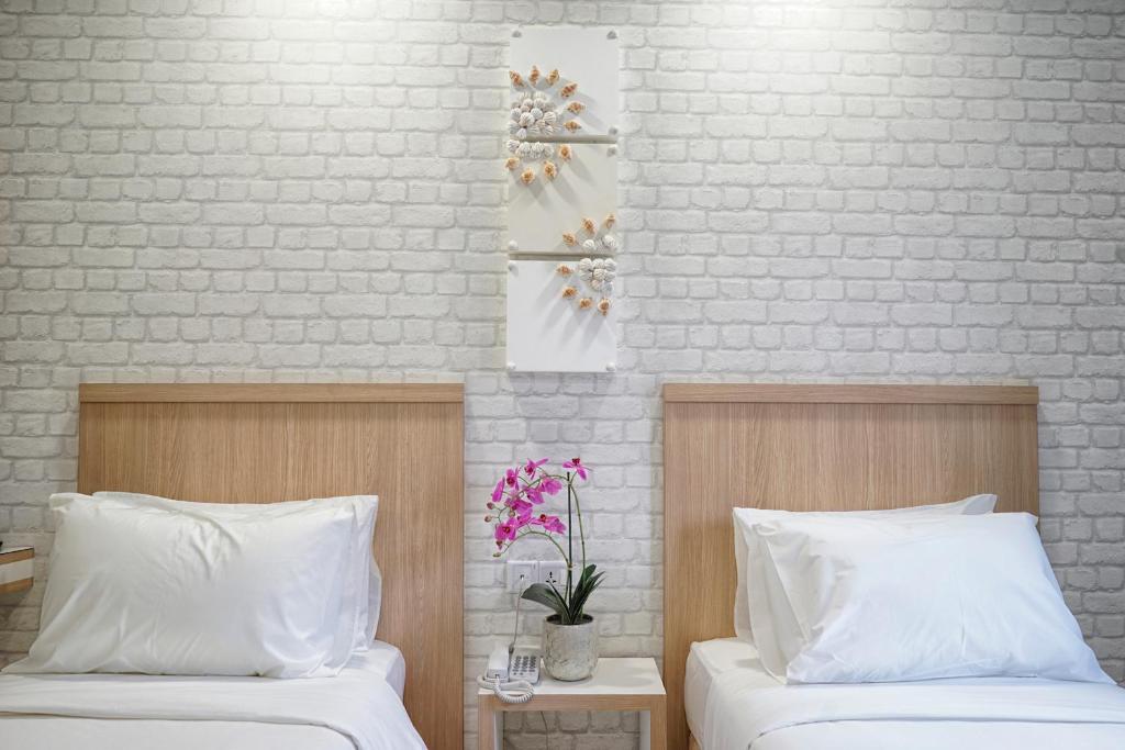 1 dormitorio con 2 camas y pared de ladrillo en LightHouse Hotel & ShortStay @ Damansara Uptown, en Petaling Jaya