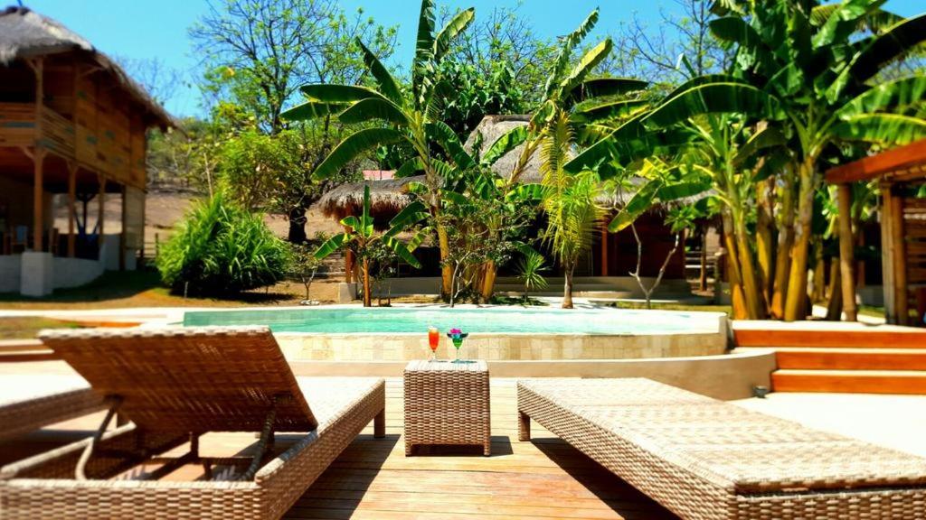 a resort with a swimming pool and two chairs and a table at Jati Village, Party Hostel and Bungalows in Gili Trawangan