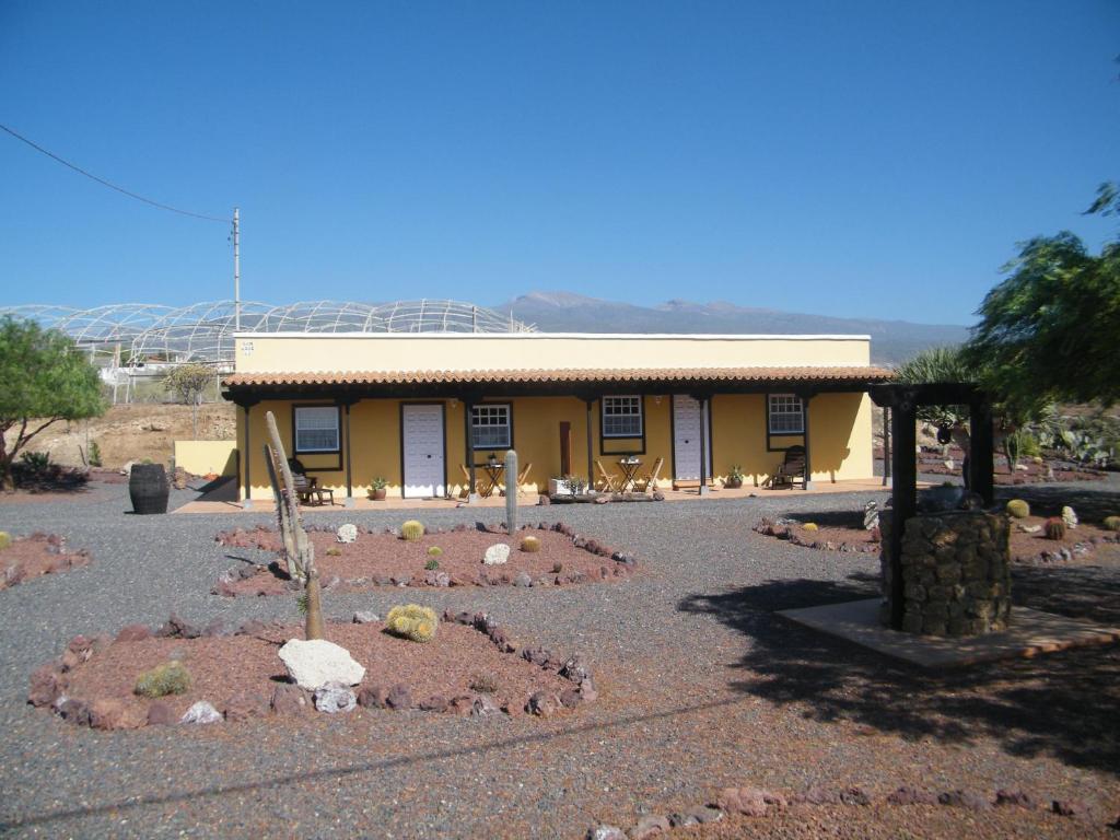 un edificio amarillo con un jardín delante de él en Casa Rural San José en San Isidro