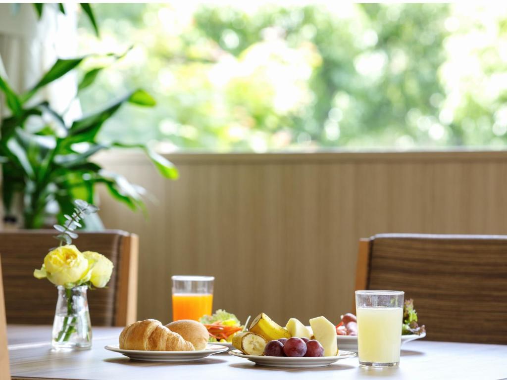 einen Tisch mit Teller mit Lebensmitteln und Gläsern Orangensaft in der Unterkunft Okayama Koraku Hotel in Okayama