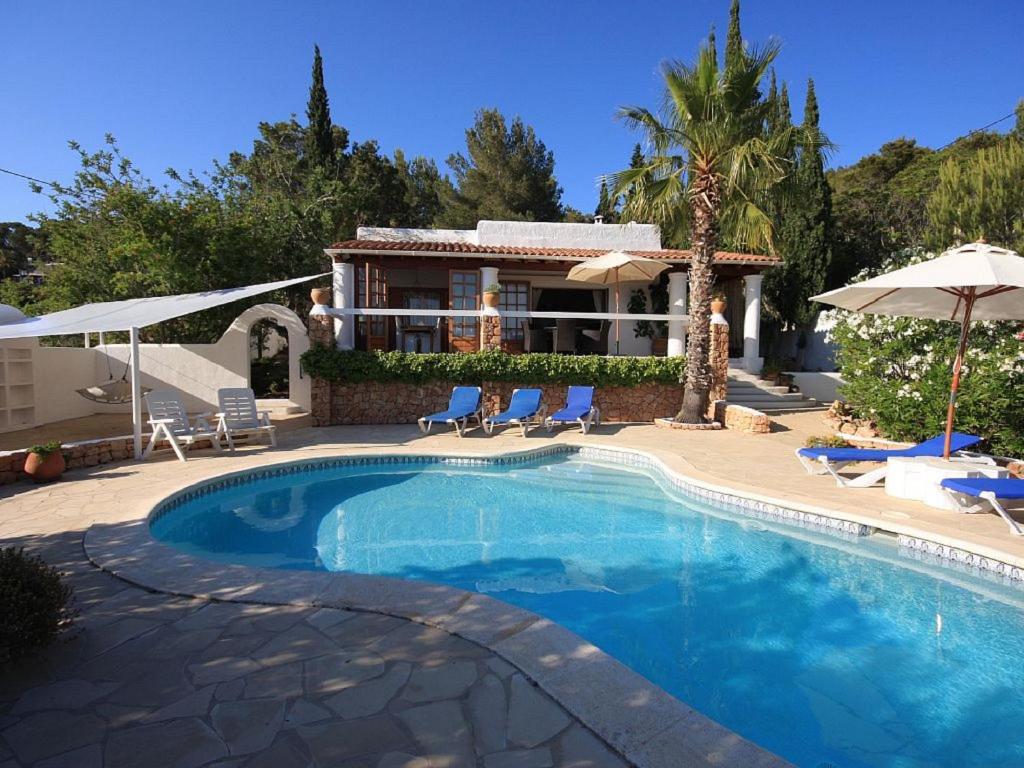 una piscina con sedie e una casa di Can Alinda a Santa Eularia des Riu