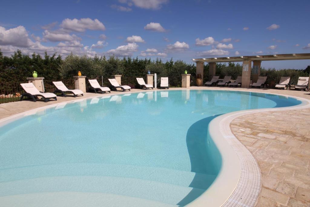 a large swimming pool with chairs and a gazebo at Il Gabellota Resort in Alberobello