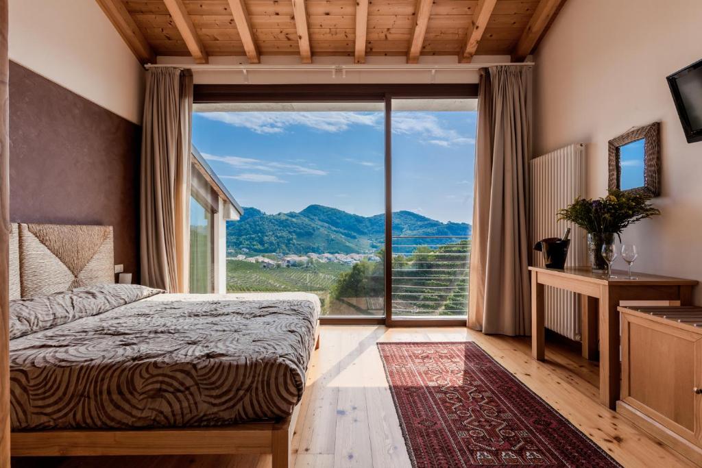 a bedroom with a bed and a large window at Agriturismo due Carpini in Valdobbiadene