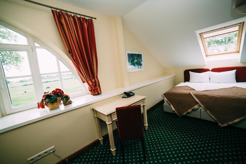 a bedroom with a bed and a table and window at Bistrampolis Manor in Kučiai