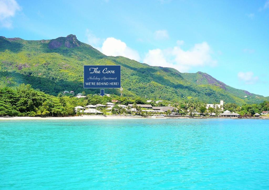 ein Strand mit einem Schild, das die Bucht mit einem Resort liest in der Unterkunft The Cove Holiday Apartment in Bel Ombre