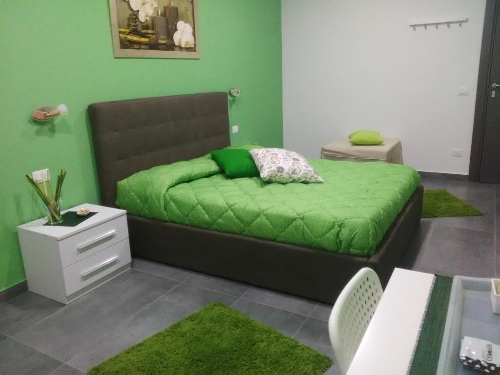 a green bedroom with a bed with a green blanket at B&B La Grotta in Nicolosi