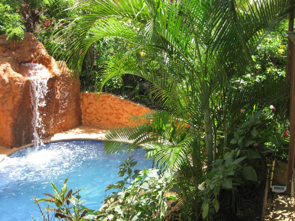 a swimming pool with a waterfall in a garden at Roatan Backpackers' Hostel in Sandy Bay