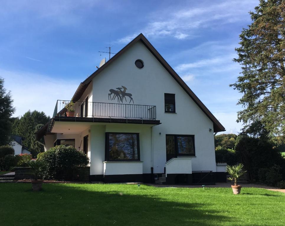 ein weißes Haus mit einem Balkon und einem Hof in der Unterkunft Villa Heidi in Solingen
