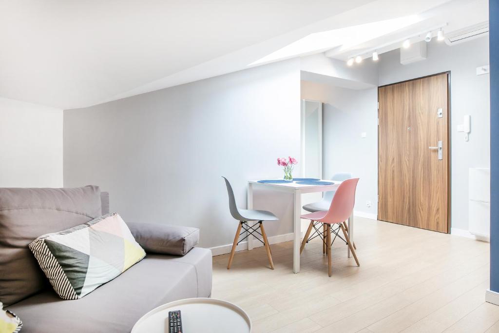 Open living area with gray sofa, colorful cushion, small dining table and wooden entry door.