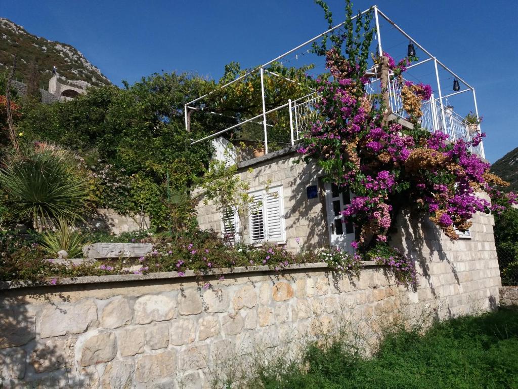 un mur en pierre avec des fleurs sur lui dans l'établissement Apartman Matić, à Ston