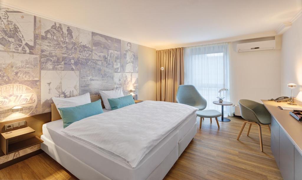 a bedroom with a large white bed and a desk at Aquis Grana City Hotel in Aachen