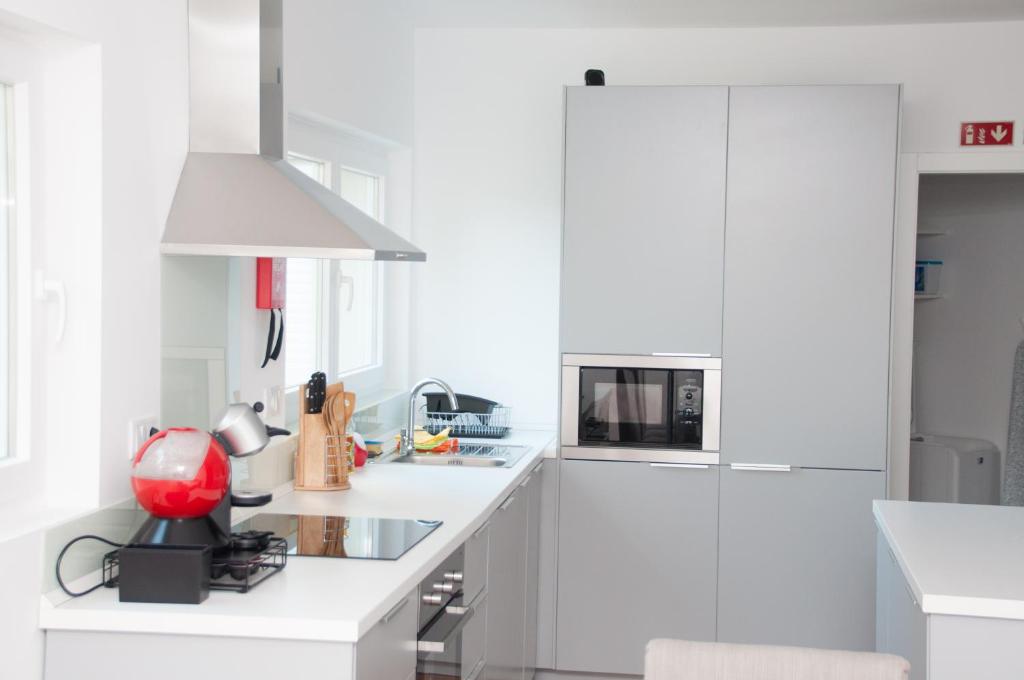 a white kitchen with white cabinets and a red appliance at Pine Tree Villa in Cascais