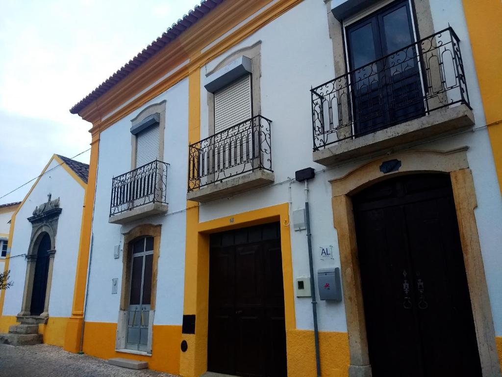 Sardoal的住宿－Casa Sardoal，白色和黄色的建筑,设有黑色的门和阳台