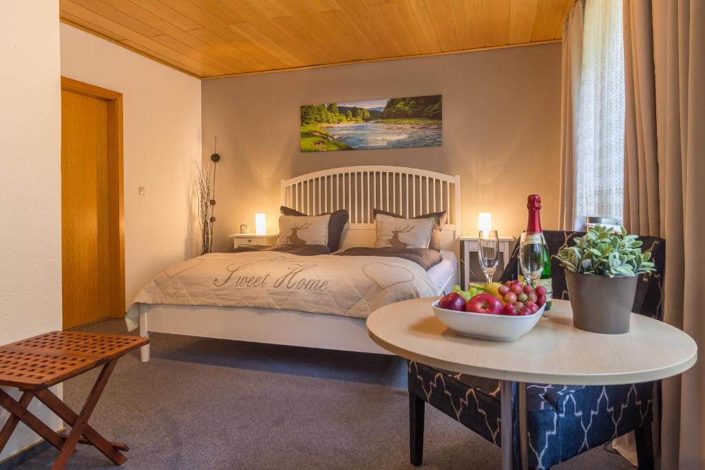 Un dormitorio con una cama y una mesa con un bol de fruta en Pension Trautheim - Am Stadtpark, en Bad Harzburg