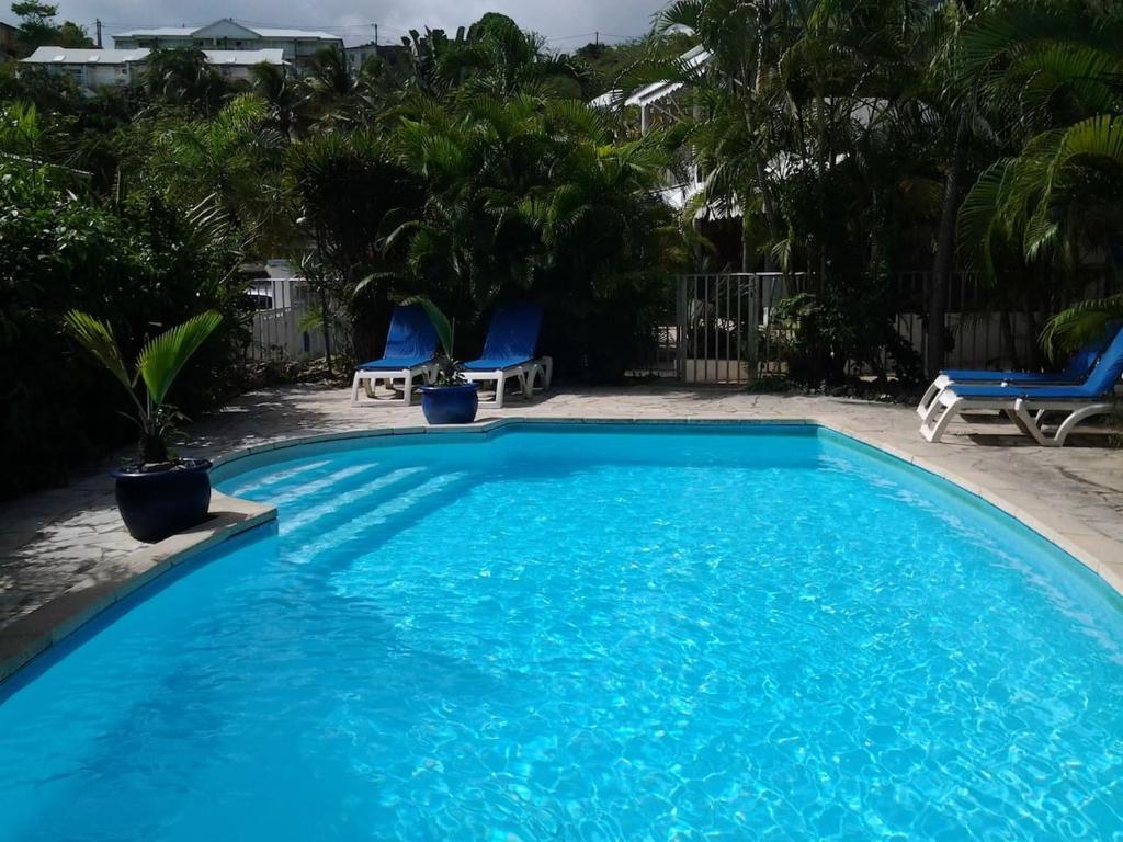 a large blue swimming pool with blue chairs and trees at RESIDENCE BLEU MARINE (Appartement Bleu Océan) in Le Gosier