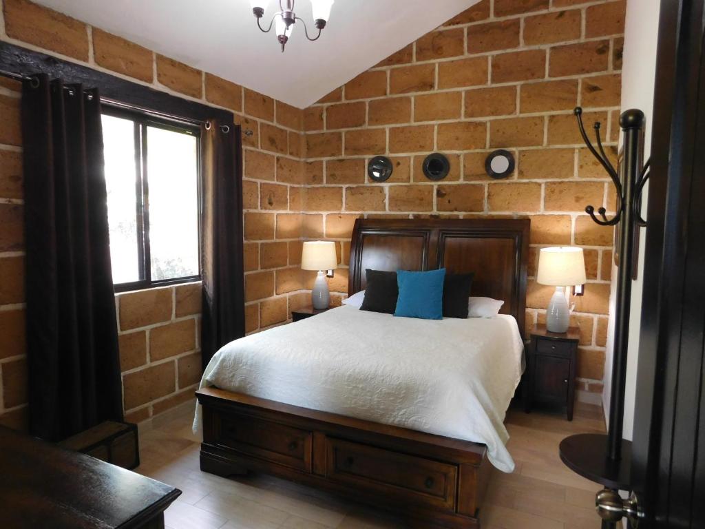 1 dormitorio con cama y pared de ladrillo en Cabañas Rancho San Jorge, en Bernal