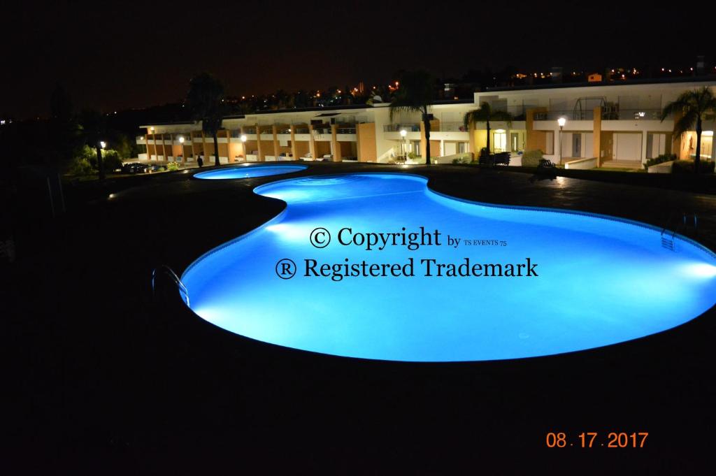 a row of blue swimming pools at night at Vila Branca in Mosqueira