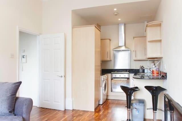 a kitchen with white cabinets and a stove top oven at Camden Apartment A/Apartment in London