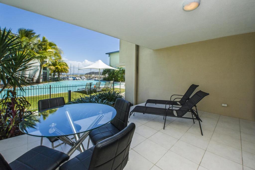 a patio with a table and chairs and a pool at Blue on Blue Apartment 813 in Nelly Bay