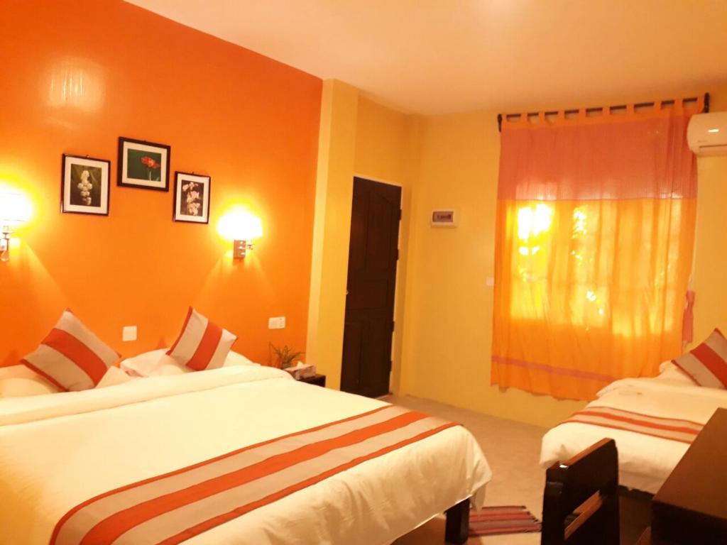 two beds in a room with orange walls at The Villager lodge in Ngapali