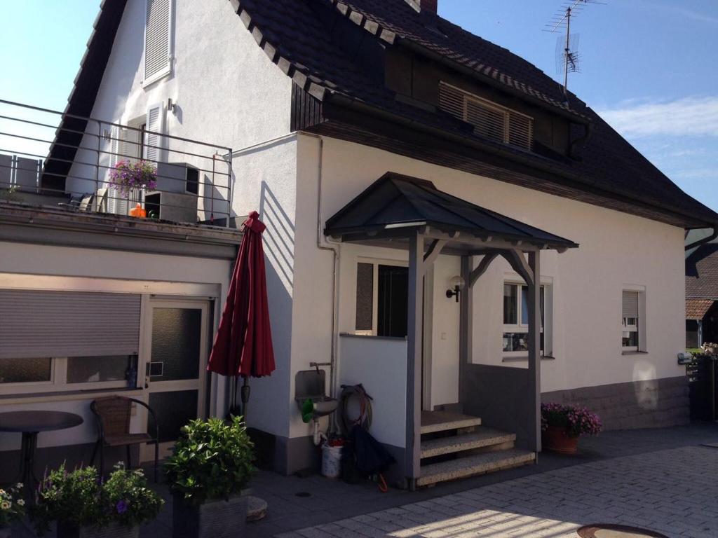 ein weißes Haus mit einem Sonnenschirm und einer Terrasse in der Unterkunft Casa Christina in Orschweier