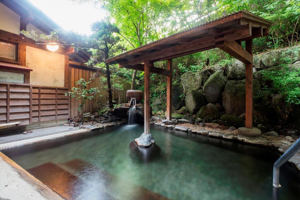 a pool of water in a garden with a waterfall at Yufuin Besso Shikisai Hotel in Yufu