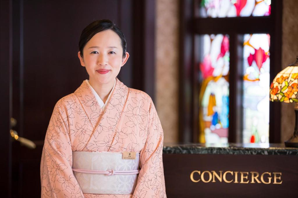 a woman in a pink robe standing in a church at Kanazawa Hakuchoro Hotel Sanraku -Natural Hot Spring- in Kanazawa