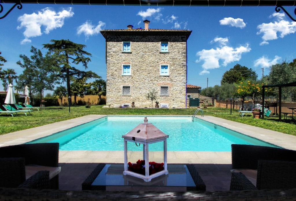 una piscina di fronte a un edificio con torre di Villa Il Palazzo a Cortona
