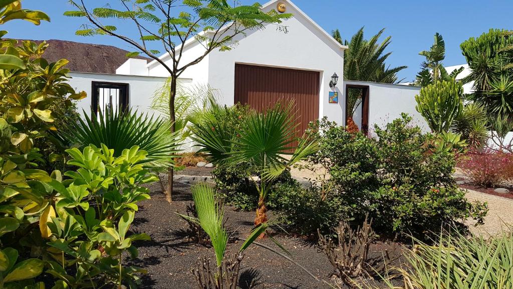 un jardín frente a una casa blanca con plantas en Lovely Villa Nico Playa Blanca, hot tub, communal pool, en Playa Blanca