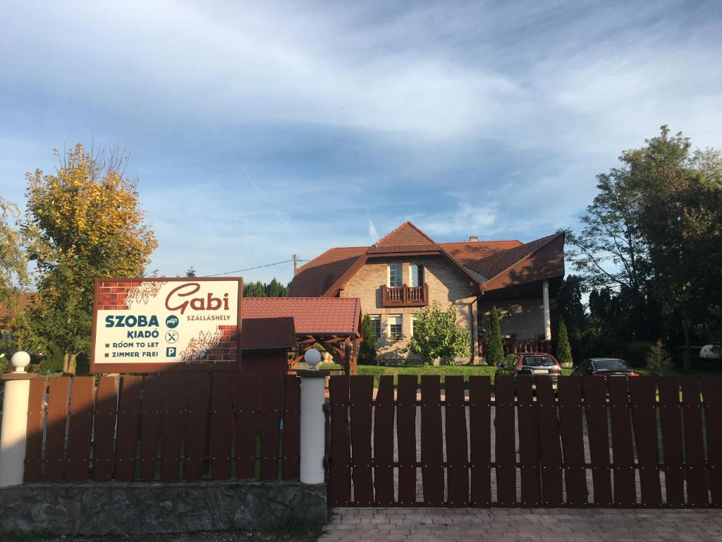 una casa con un cartel delante de una valla en Gabi Magánszálláshely, en Zalasárszeg