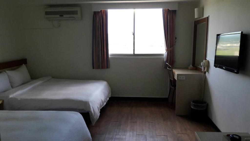 a hotel room with two beds and a window at Light Blue Hostel in Hengchun South Gate