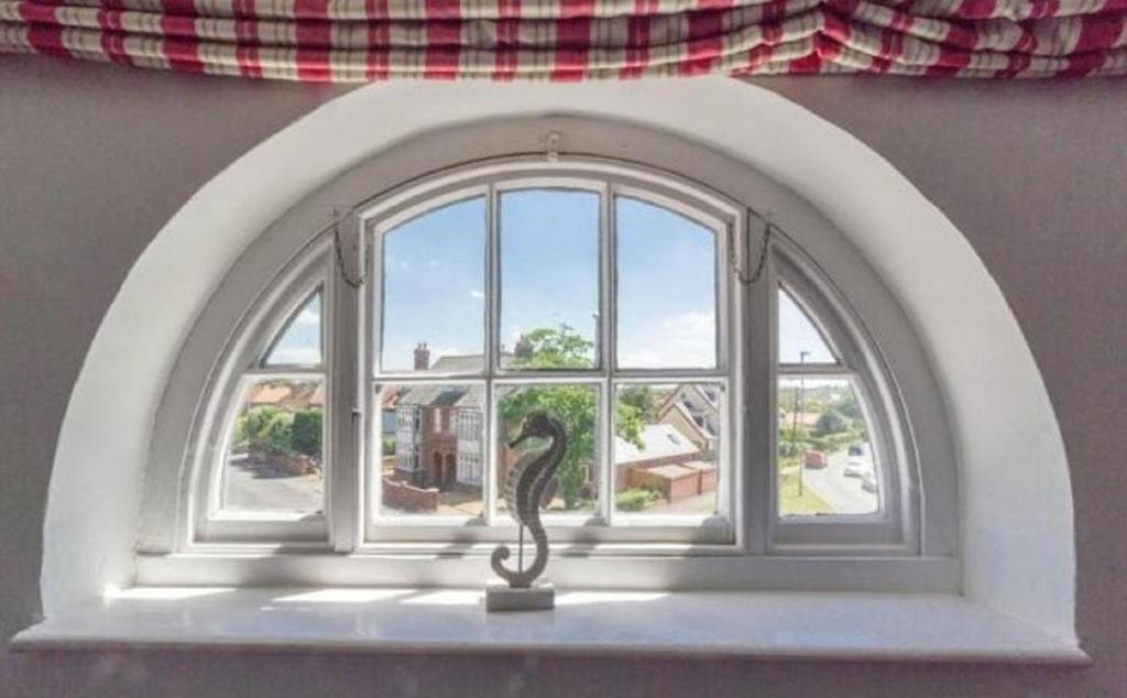 an arched window with a cat statue in front of it at The Globe Inn in Wells next the Sea