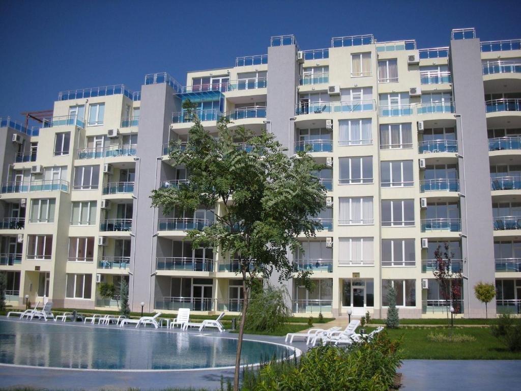 a large building with a swimming pool in front of it at Oasis Suites Apartments and Studios in Ravda