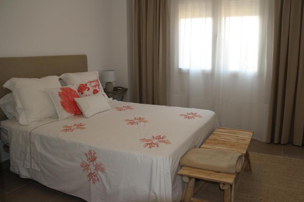 1 dormitorio con 1 cama blanca con almohadas y silla en NEW!! Bonito adosado en Zahara de los Atunes, en Zahara de los Atunes