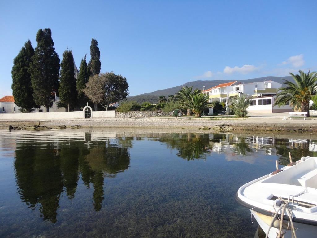 un barco en un cuerpo de agua con casas y árboles en Apartments Ana en Sreser