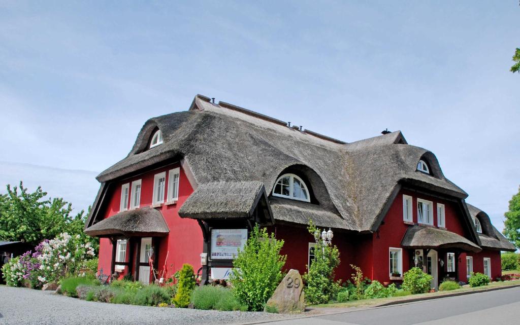 Neu ReddevitzにあるKarolas Landhus unterm Reetdachの茅葺き屋根の赤い家