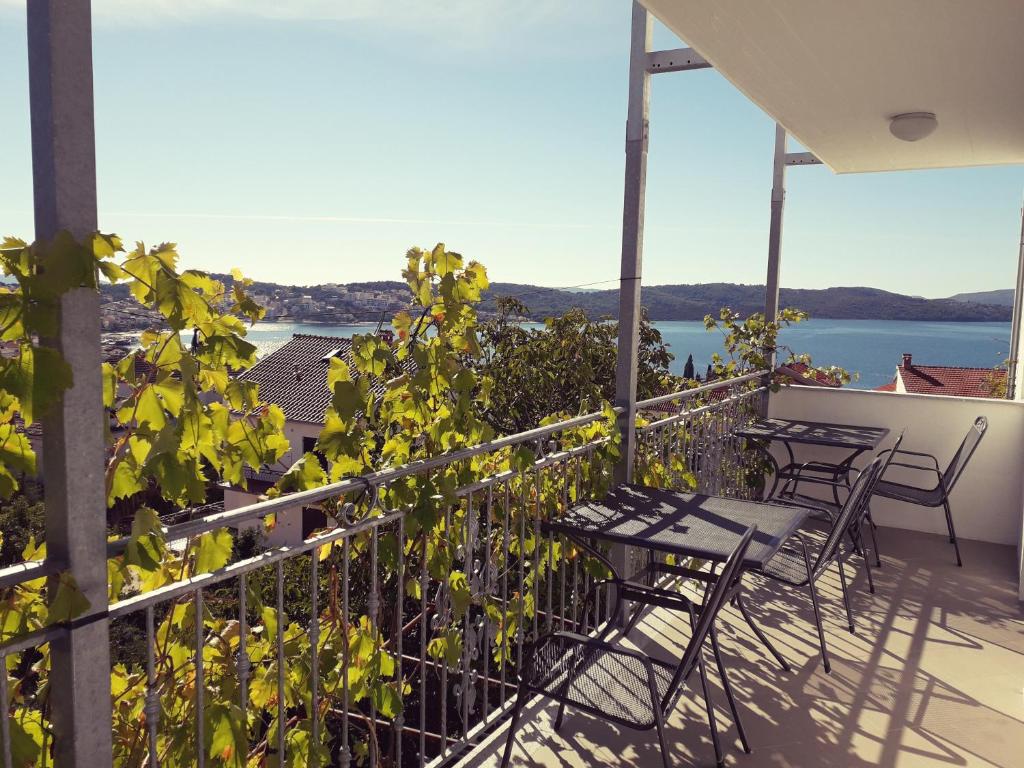 einen Balkon mit Tischen und Stühlen und Blick auf das Wasser in der Unterkunft Apartments Babić in Trogir