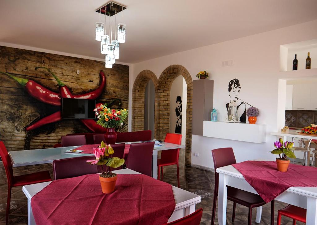 ファヴァーラにあるB&B Vento di Sciroccoの白いテーブルと赤い椅子が備わる壁のレストラン