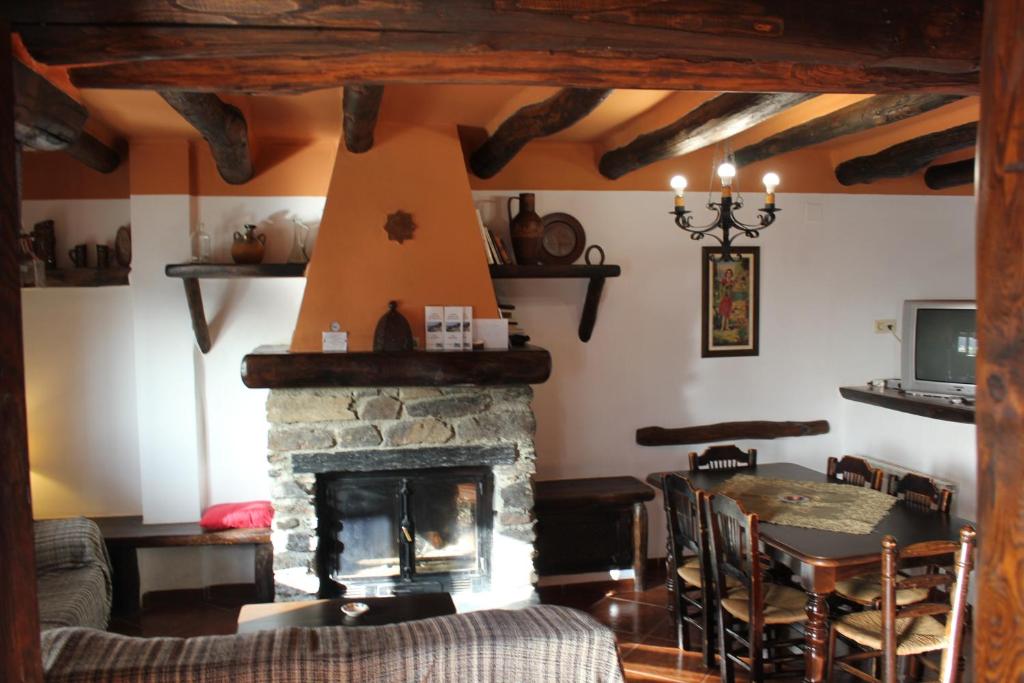 sala de estar con chimenea de piedra y mesa en Casas Rurales Encarnita, en Bubión