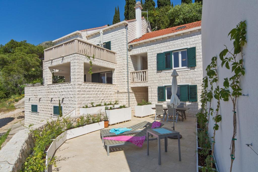 a house with a patio with chairs and a table at I Sassi Bianchi - East Villa in Cavtat