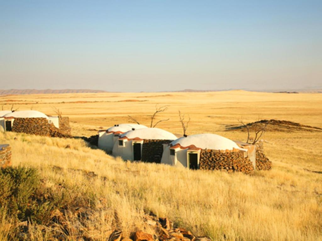 eine Gruppe von Hütten auf einem Feld in der Wüste in der Unterkunft Rostock Ritz Desert Lodge in Cha-re