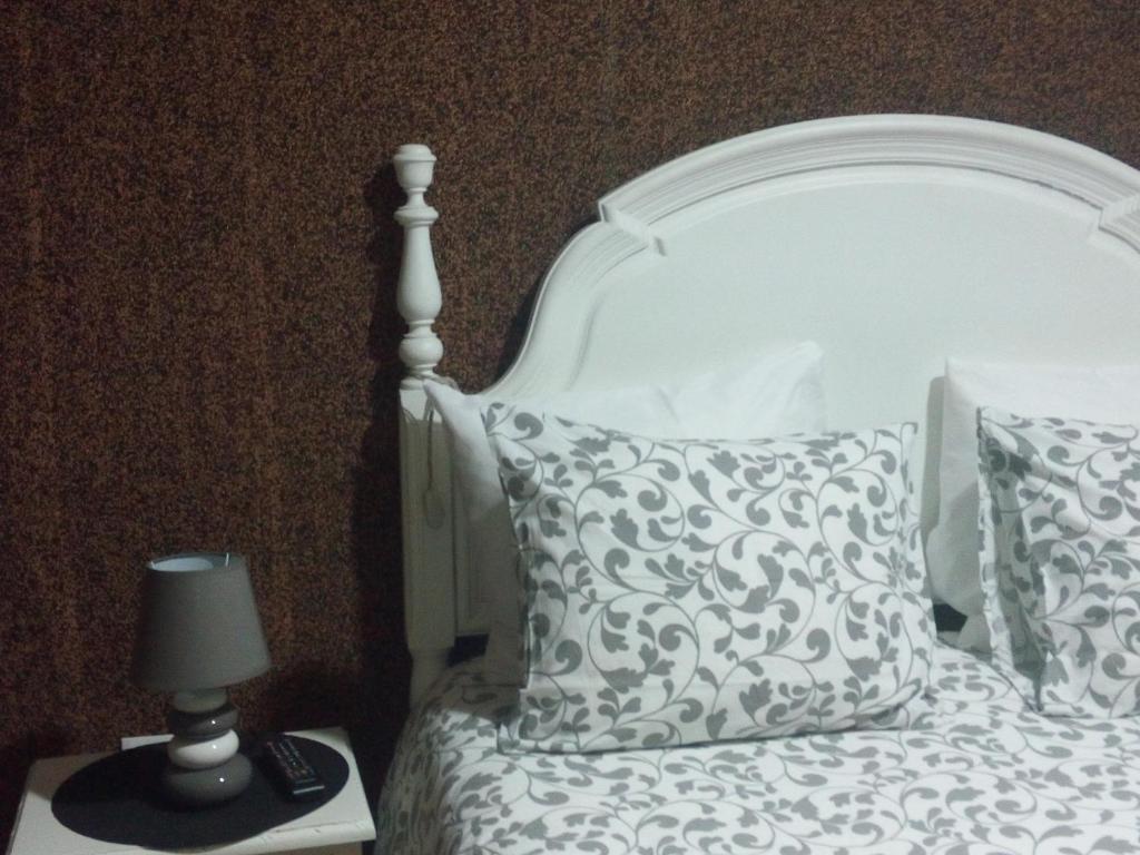 ein weißes Bett mit einem Kissen und einer Lampe in der Unterkunft Jualis Guest House in Porto