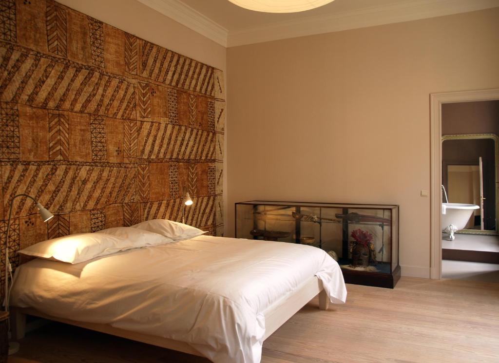 a bedroom with a bed and a wall with a mirror at Le Vaudeville in Brussels