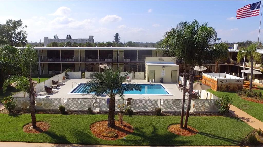 an aerial view of a building with a pool and palm trees at At Home Inn - Fort Pierce in Fort Pierce