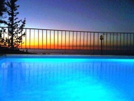 a large swimming pool with the sunset in the background at Agios Nikitas Resort Villas in Agios Nikitas