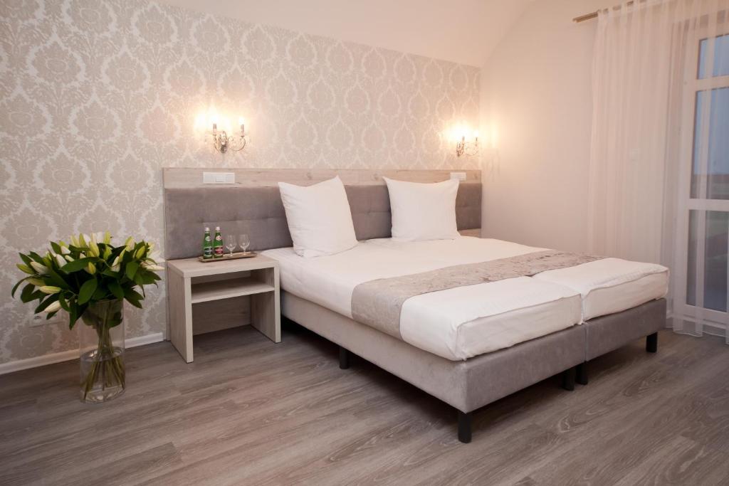 ein Schlafzimmer mit einem Bett und einer Vase aus Blumen in der Unterkunft Dworek Bukowy Park in Stettin