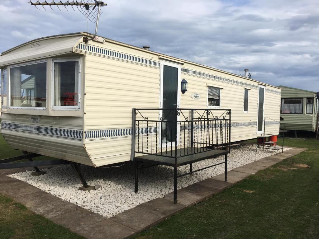 a white rv parked on gravel in a yard at Taylor's Caravan Holiday's 8 Berth (Coral Beach) in Ingoldmells